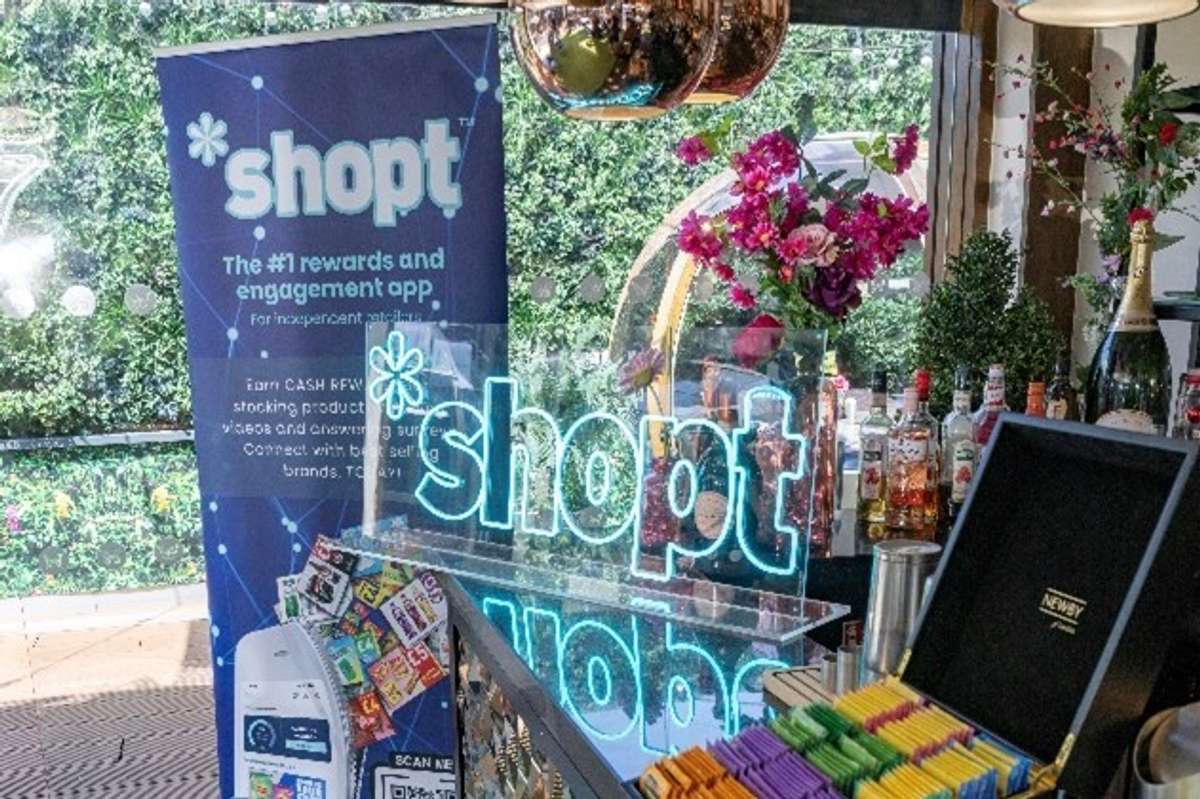 Shopt summer event display with neon logo, drinks, and flowers