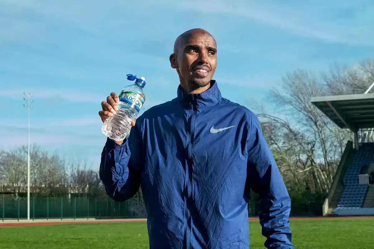 Sir Mo Farah holding a bottle of Buxton