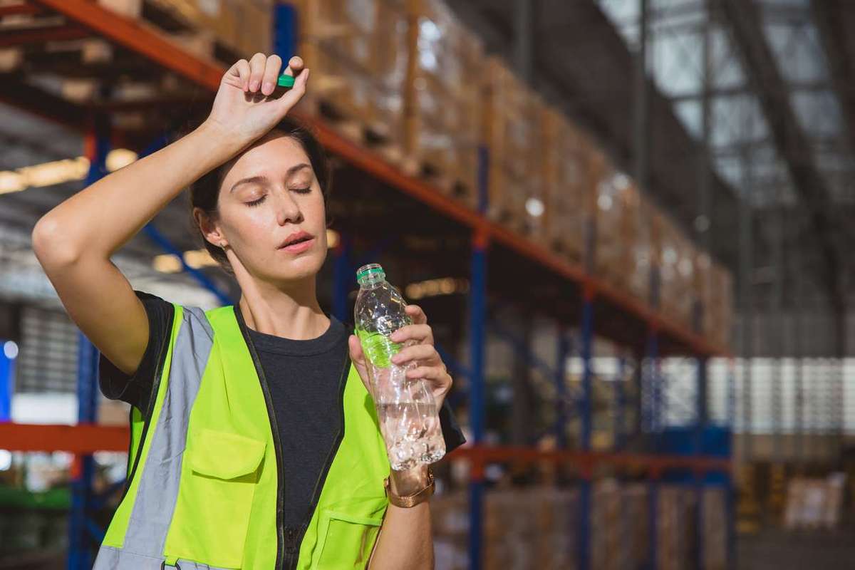staff worker sweats from hot weather in summer working in warehouse