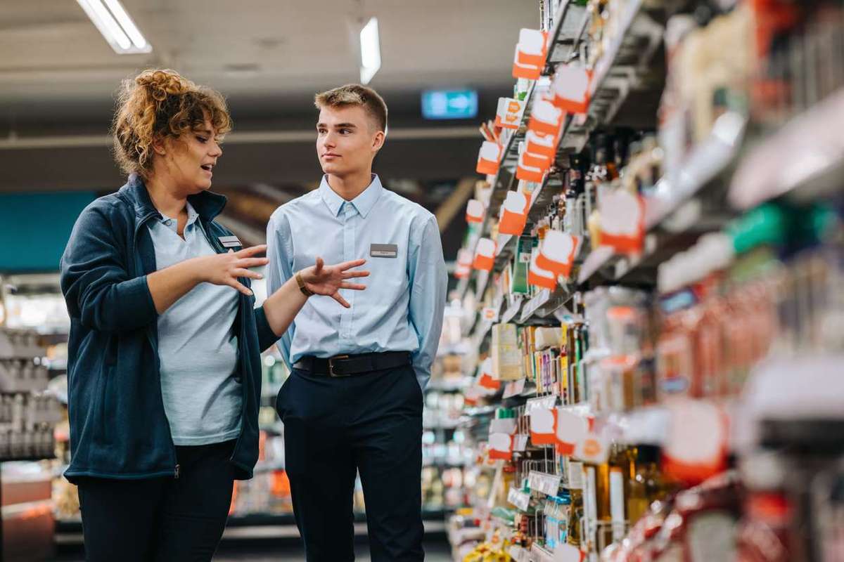 Supermarket manager giving training to a young worker