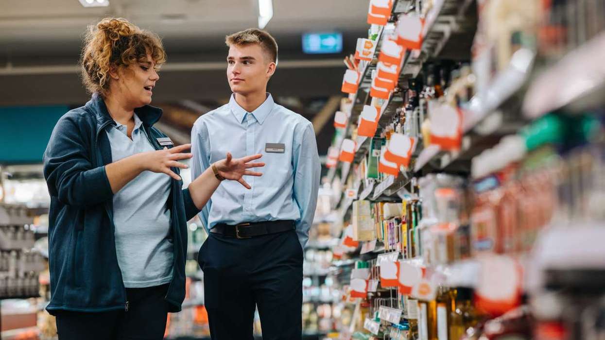 Supermarket manager giving training to a young worker