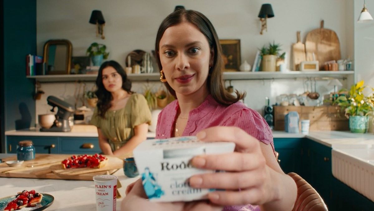 Woman offers Rodda’s clotted cream during dessert prep in vibrant kitchen scene from TV ad