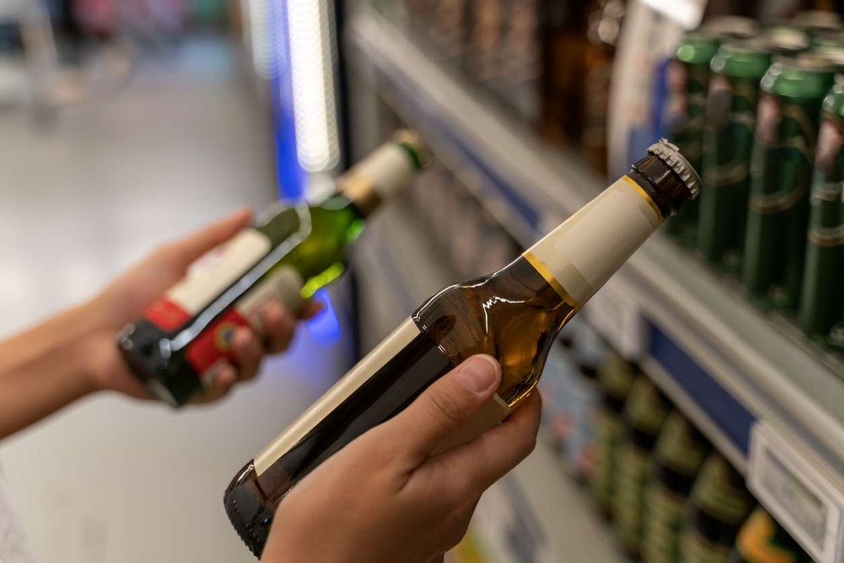 woman picks a beer from the beverage aisle