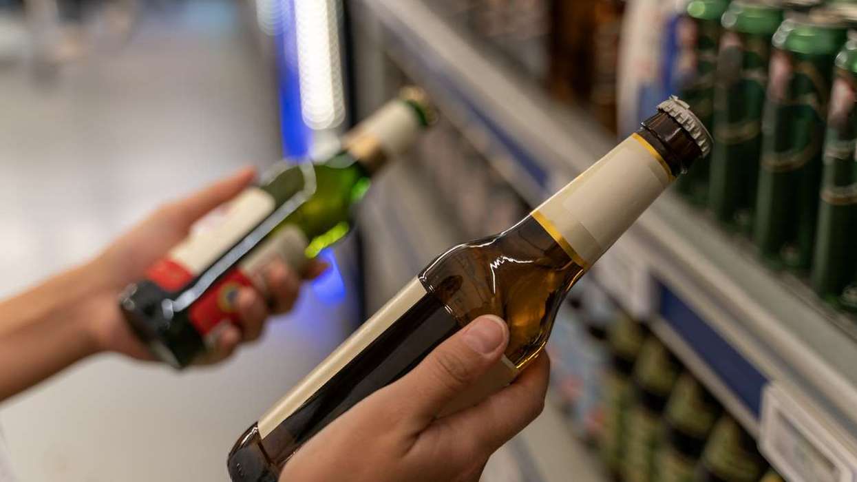 woman picks a beer from the beverage aisle
