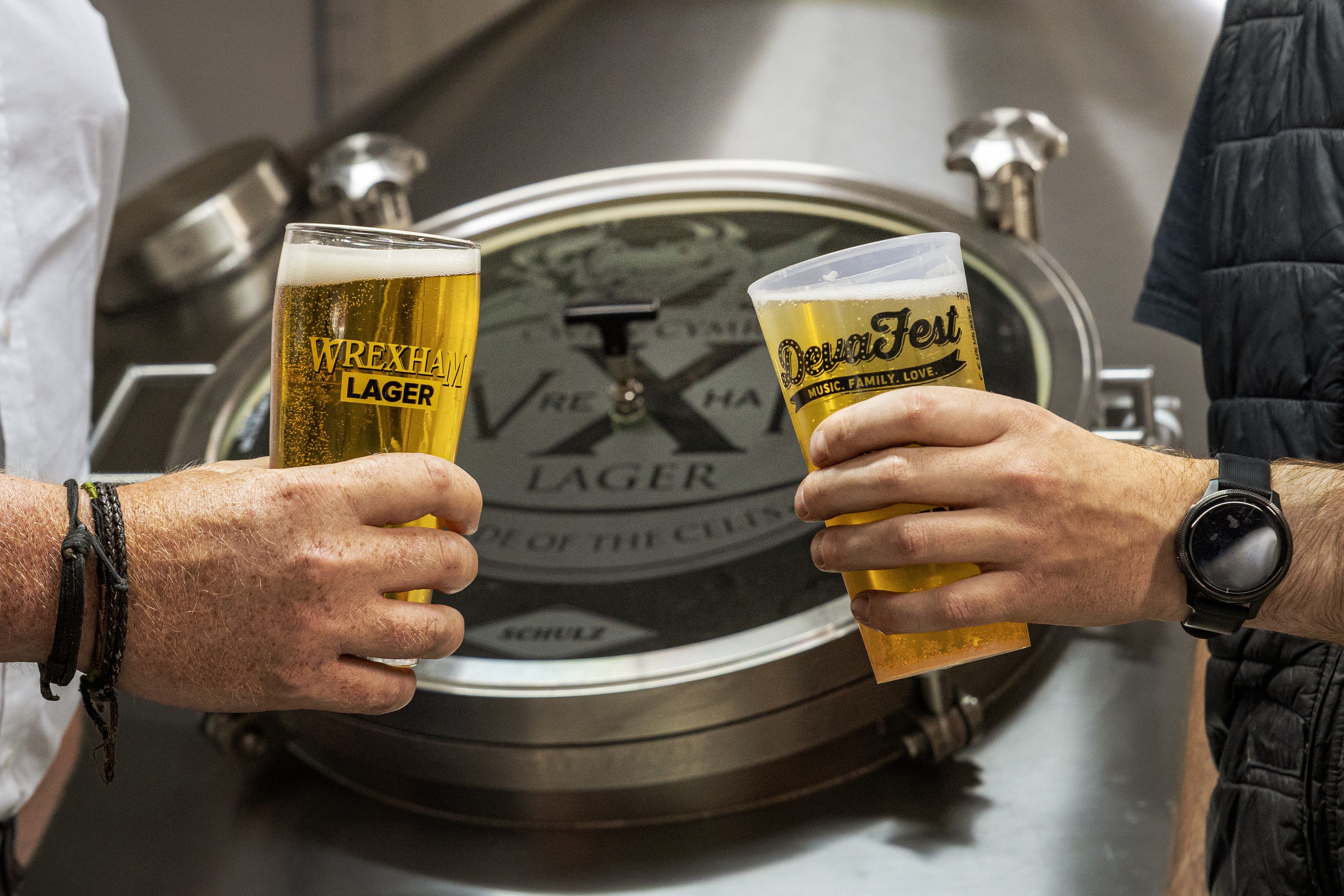 Wrexham Lager and Deva Fest branded pints clinked in celebration at the brewery