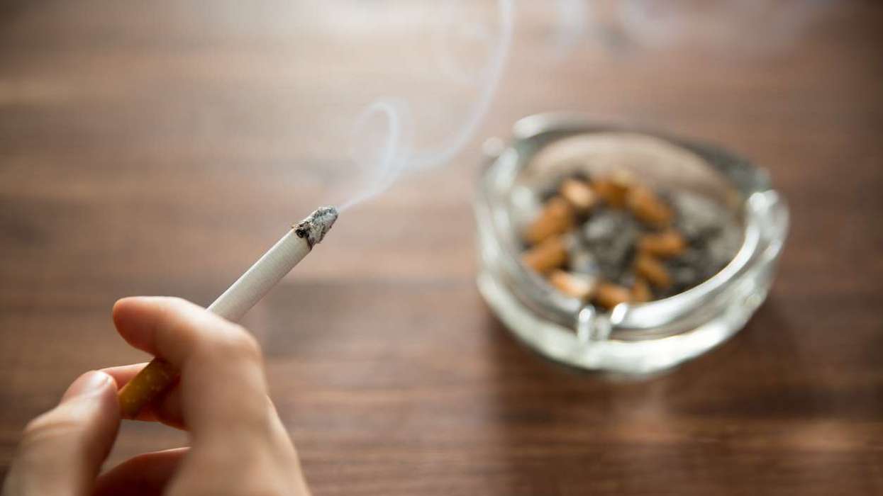 Young woman holding burning cigarette in hand