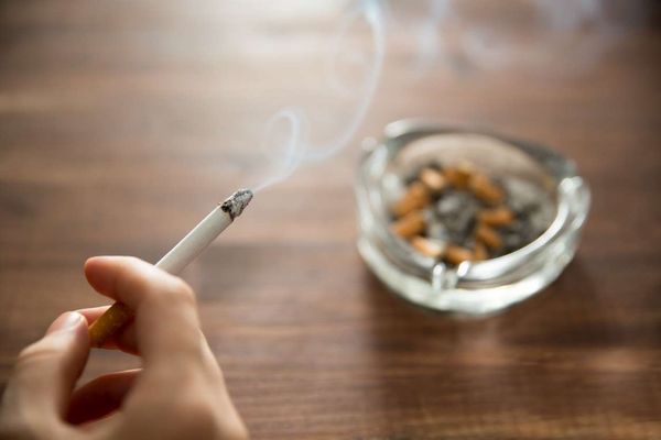 Young woman holding burning cigarette in hand